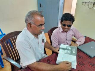 graphic நூலை சரவணமணிகண்டனுக்கு வாசித்துக் காட்டுகிறார் பாஸ்கர்